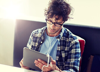 Image showing man with tablet pc and earphones sitting at cafe