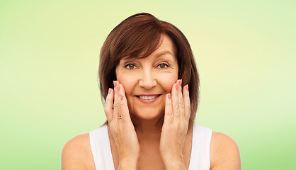 Image showing portrait of smiling senior woman touching her face