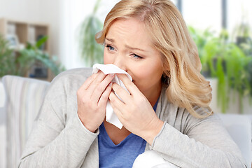 Image showing ill woman blowing nose to tissue at home