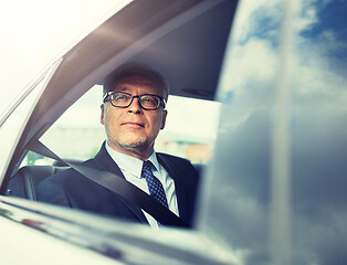 Image showing senior businessman driving on car back seat