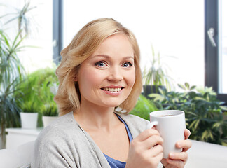 Image showing smiling woman with cup of tea or coffee at home