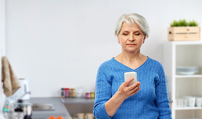 Image showing senior woman using smartphone at kitchen