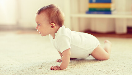 Image showing little baby in diaper crawling on floor at home