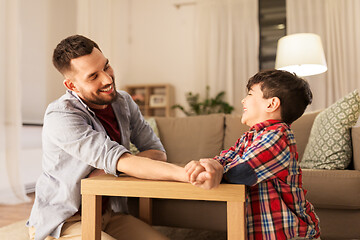 Image showing happy father and little son arm wrestling at home