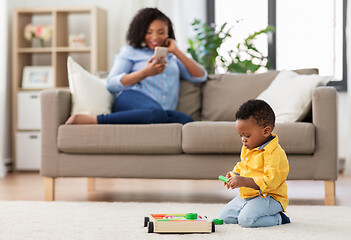 Image showing baby playing toy blocks and mother with smartphone