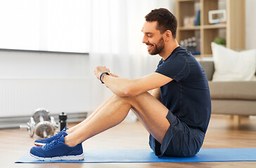 Image showing smiling man with fitness tracker exercising at home