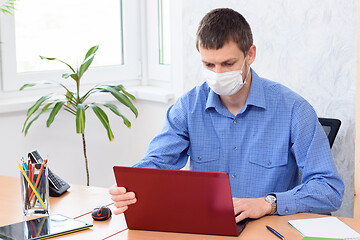 Image showing Office clerk working at a computer in a medical mask