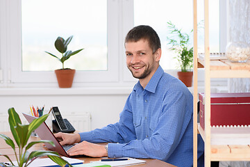 Image showing Successful young man in the office works in the computer and looked into the frame