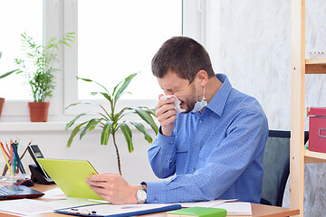 Image showing Ill office worker sneezes at work place