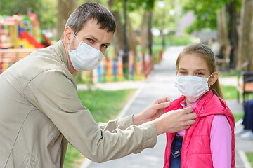 Image showing Dad on the street puts on his daughters face a medical mask, looked into the frame