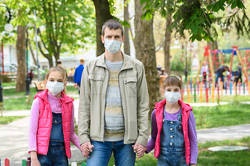 Image showing Dad and two daughters are in protective medical masks at the playground