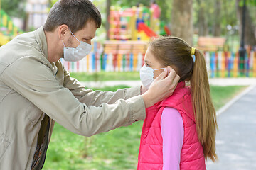 Image showing Dad puts on his daughters face a medical mask