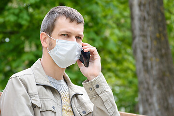 Image showing Portrait of a man in a medical mask talking on the phone