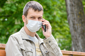 Image showing Close-up of a masked man with a phone on the street, looked into the frame