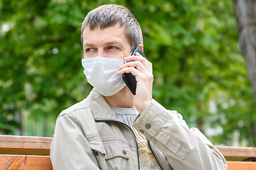 Image showing Close-up of masked man with phone on the street