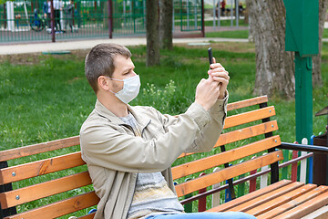 Image showing A man in a medical mask is photographed on the phone