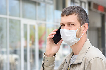 Image showing Portrait of a masked man with a mobile phone in the background of the store