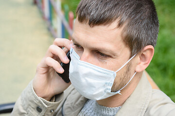 Image showing Close-up of a man in a medical mask talking on the phone