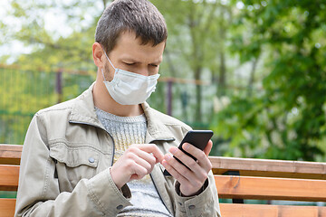 Image showing A man on a walk looks at the screen of a mobile phone