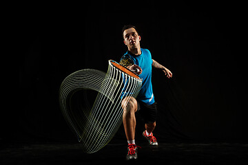 Image showing Young male badminton player over balck background