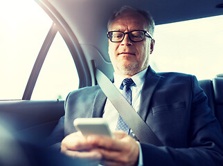 Image showing senior businessman texting on smartphone in car