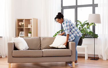 Image showing african american woman arranging sofa cushions