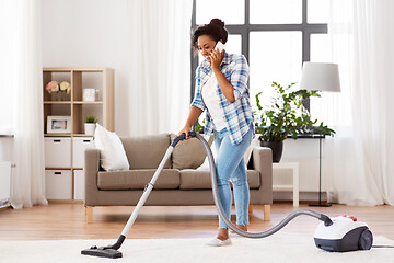 Image showing african american woman with vacuum cleaner at home