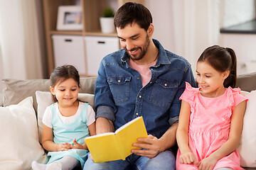 Image showing happy father with daughters reading book at home