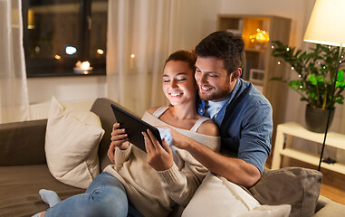 Image showing happy couple using tablet pc at home in evening