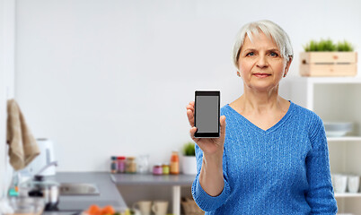 Image showing senior woman showing smartphone at kitchen