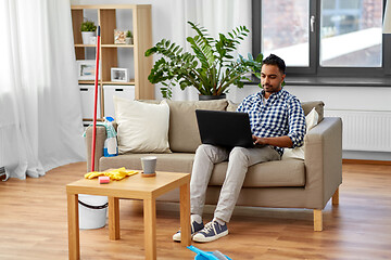 Image showing man with laptop computer after home cleaning