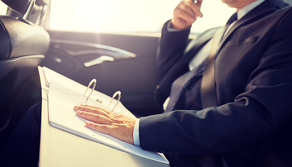 Image showing senior businessman with papers driving in car