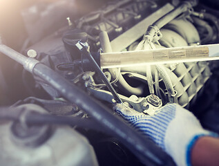 Image showing mechanic man with wrench repairing car at workshop