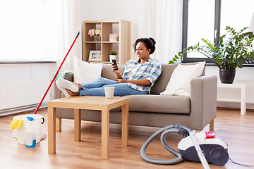 Image showing woman with smartphone resting after home cleaning