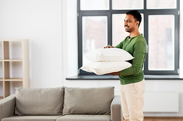 Image showing happy indian man holding pillows at home