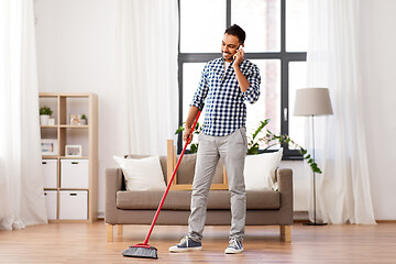 Image showing man with broom cleaning and calling on smartphone