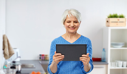 Image showing senior woman using tablet computer at kitchen