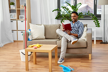 Image showing man reading book and resting after home cleaning