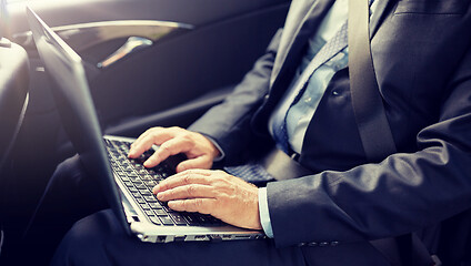 Image showing senior businessman with laptop driving in car