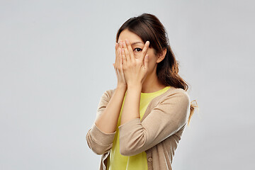 Image showing scared asian woman peeking