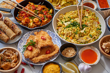 Image showing Asian food served. Plates, pans and bowls full of noodles chicken stir fry and vegetables