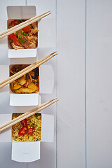 Image showing Three take away paper boxes filled with asian food placed in row on white