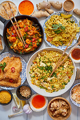 Image showing Asian food served. Plates, pans and bowls full of noodles chicken stir fry and vegetables