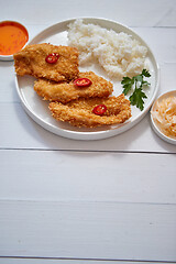 Image showing Crispy chicken fried in breadcrumbs served with rice. View from the top on white wooden background