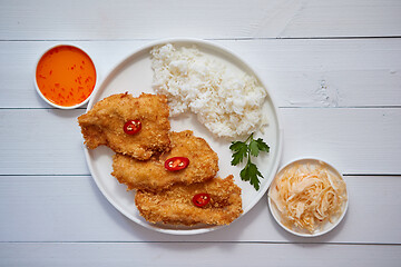 Image showing Crispy chicken fried in breadcrumbs served with rice. View from the top on white wooden background