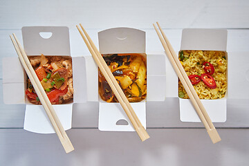 Image showing Three take away paper boxes filled with asian food placed in row on white