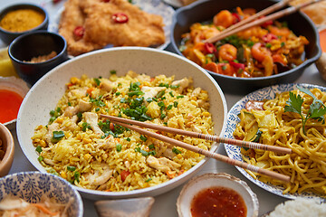 Image showing Asian food served. Plates, pans and bowls full of noodles chicken stir fry and vegetables