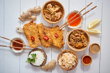 Image showing Deep fried Crispy chicken in breadcrumbs served on white wooden table with salad, spices