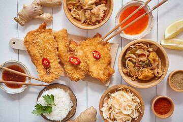 Image showing Deep fried Crispy chicken in breadcrumbs served on white wooden table with salad, spices