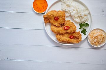 Image showing Crispy chicken fried in breadcrumbs served with rice. View from the top on white wooden background